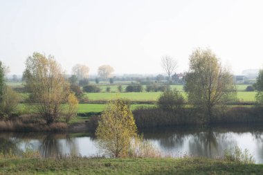 Hollanda 'da küçük bir nehrin önünde duran eski Hollandalı ev, tipik bir Hollanda doğası sahnesi sonbaharda çekildi