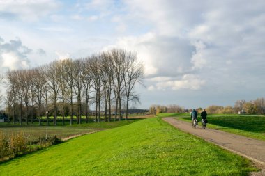 Hollandalılar Weurt ve Beuningen arasında Gelderland 'de bir hendekte bisiklet sürerken, fotoğraf sonbaharda güneşli bir günde çekildi.