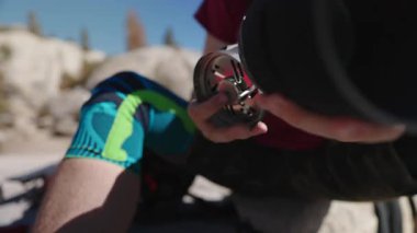 A person is setting up a hiking remote gas stove immersed in natures beauty, preparing for an exciting photography shoot while enjoying the peaceful surroundings