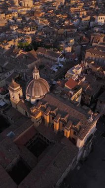 Aerial footage showcases the charming architecture of a historic city, illuminated by warm sunset hues, creating a mesmerizing atmosphere as day turns to night