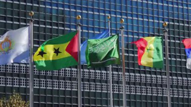 New York 10.28.2025. Birleşmiş Milletler 'in Manhattan' daki karargahının cam önünde sallanan renkli uluslararası bayraklar, barış, diplomasi ve dünya birliğini temsil ediyor..