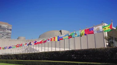 New York 10.28.2025. Manhattan 'daki Birleşmiş Milletler Genel Merkezi' nin dışındaki renkli uluslararası bayrakların panoramik görüşü barışı, dünya birliğini ve küresel işbirliğini simgeliyor.