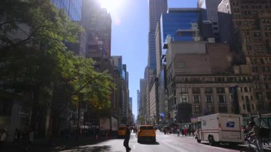 New York 10.28.2025. Yoğun trafiği, sarı taksileri ve New York 'taki yüksek binaları olan güneşli şehir merkezi caddesi, seyahat, kentsel yaşam tarzı ve modern şehir temaları için uygun canlı bir şehir atmosferi yaratıyor.