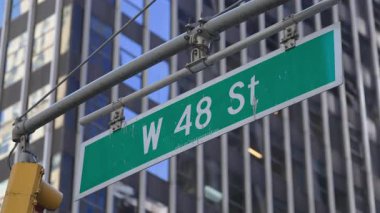New York City, New York 'ta uzun yansıtıcı gökdelenleri olan W 48. Cadde tabelası, mimari, seyahat, navigasyon ve modern şehir manzarası temalı görseller için uygun temiz bir şehir manzarası yaratıyor.