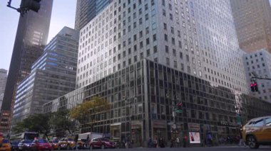 New York 10.28.2025. New York şehir merkezindeki yüksek cam ofis binaları. Sarı taksiler ve yoğun bir şehir caddesi boyunca ilerleyen sabit trafik. Stok kullanımı için uygun temiz, modern bir şehir manzarası yaratıyor.