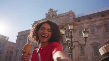 Roma 'nın canlı bir meydanında renkli dondurmalar taşıyan gülümseyen turist sıcak güneş ışığı ve klasik taş binalarla neşeli bir tatil atmosferi yaratıyor..