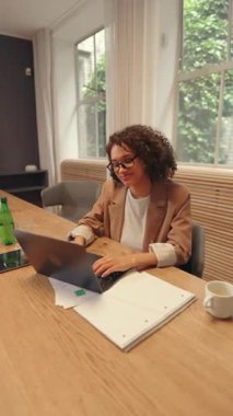 Çalışma arkadaşları parlak bir ofis ortamında yaptıkları verimli bir toplantıda fikir ve geri bildirim alışverişinde bulunurken, takım tartışması bir dizüstü bilgisayarın etrafında grafikler ve tabletle açılır..