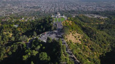 Griffith Gözlemevi 'nin insansız hava aracı görüntüsü yoğun Los Angeles California şehir şebekesine bakıyor yeşil park çimleri, yollar, arabalar ve temiz gökyüzü..