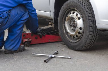 Tamirci vida değiştiriyor ya da söküyor. İngiliz anahtarı tamircisi iş yerinde bir arabanın tekerleğini değiştiriyor.