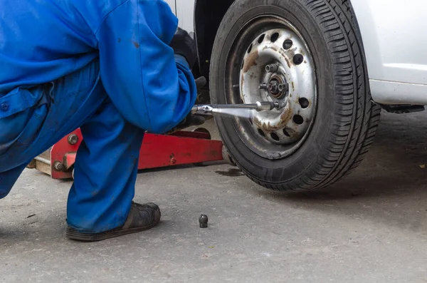 Tamirci vida değiştiriyor ya da söküyor. İngiliz anahtarı tamircisi iş yerinde bir arabanın tekerleğini değiştiriyor.