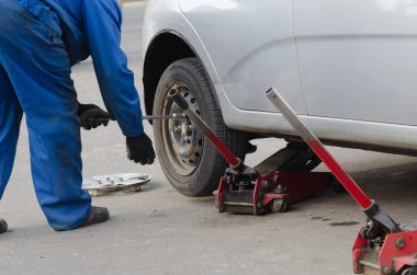 Tamirci vida değiştiriyor ya da söküyor. İngiliz anahtarı tamircisi iş yerinde bir arabanın tekerleğini değiştiriyor.