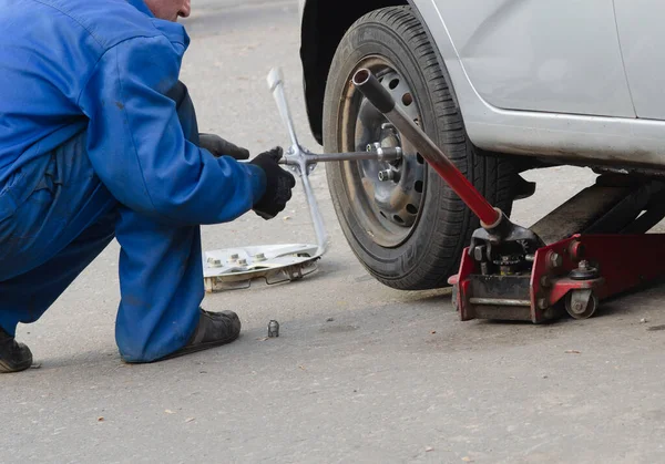 Mekaniker skruva eller skruva loss byte bil hjul med skiftnyckel mekaniker på jobbet byta hjul på en bil — Stockfoto
