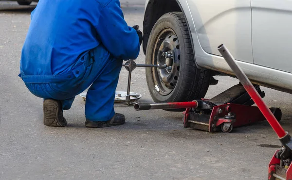 Tamirci vida değiştiriyor ya da söküyor. İngiliz anahtarı tamircisi iş yerinde bir arabanın tekerleğini değiştiriyor.