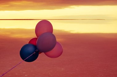 Kırmızı, mavi, pembe, mavi balonlar gün doğumunda pembe tuz gölü üzerinde Sevgililer Günü