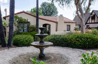 Kaliforniya, Amerika, Pasadena, bej kaplama ve kiremit çatılı bir ev. Avlunun ortasında iki katlı bir taş çeşme bulunmaktadır. Avlu çakıllarla kaplı ve yemyeşil bitki örtüsüyle çevrili..