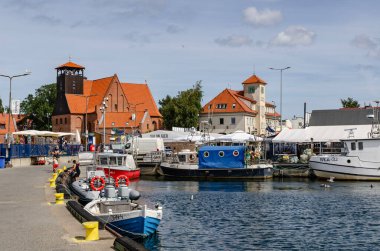 Polonya Gdynia plajı Doli Doli 11 Ağustos 2025 Limanda yüzen martılarla ve arka planda endüstriyel liman binalarıyla dolu renkli balıkçı tekneleri.