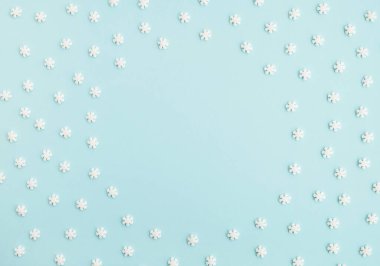 Kış ve Noel kompozisyonu. Pastel açık mavi arka planda kar taneleri tatlı konfeti yapar. Üst görünüm, çerçeve, düz görünüm, boşluğu kopyala