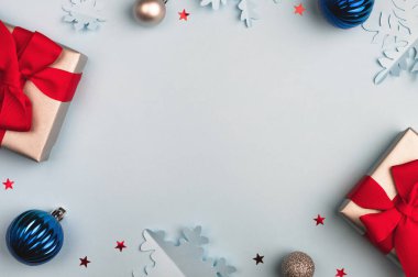 Noel ve kış kompozisyonu. Hediye kutuları, kar taneleri ve açık mavi arka planda şenlik dekoru. Üst görünüm, düz görünüm, kopyalama alanı, çerçeve