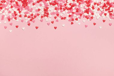 Sweet colorful heart confetti on pastel pink background. Valentines day, birthday party or mothers day minimal composition. Top view, flat lay, copy space