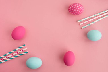 Colorful easter eggs in pastel colors and festive decor on light pink background. Minimal composition. Top view, flat lay, copy space