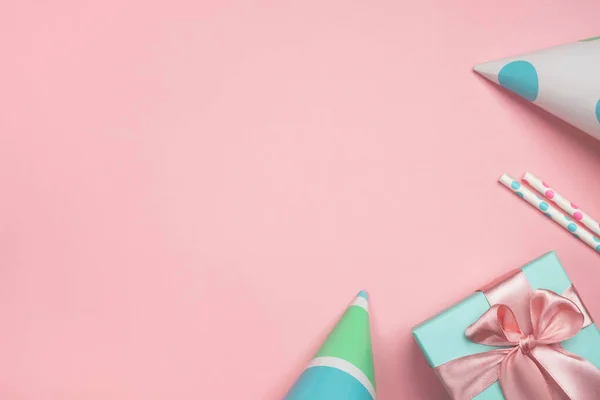 Doğum günü ya da parti geçmişi. Hediye kutusu, karnaval şapkaları ve şenlikli dekorasyonlar. Pastel pembe ve nane renginde kompozisyon. Üst görünüm, düz görünüm, kopyalama alanı