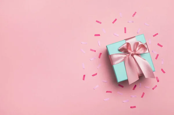 Pastel pembe arka planda hediye kutusu ve konfeti. Doğum günü partisi, sevgililer günü ya da anneler günü tebrik kartı. Üst görünüm, düz görünüm, kopyalama alanı