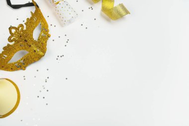 Beyaz arka planda altın parıltılı ve şenlikli Karnaval Maskesi. Parti, Mardi Gras veya Purim bayramı. Üst görünüm, düz görünüm, kopyalama alanı