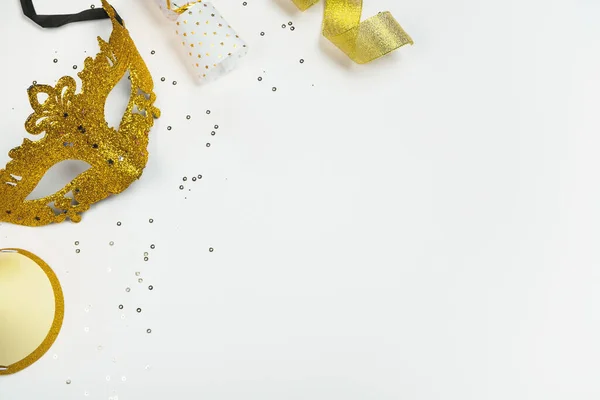 Beyaz arka planda altın parıltılı ve şenlikli Karnaval Maskesi. Parti, Mardi Gras veya Purim bayramı. Üst görünüm, düz görünüm, kopyalama alanı