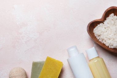 Ev için spa ürünleri. Açık pembe arka planda banyo aksesuarları. Vücut tedavisi, cilt bakımı. Üst görünüm, düz görünüm, kopyalama alanı