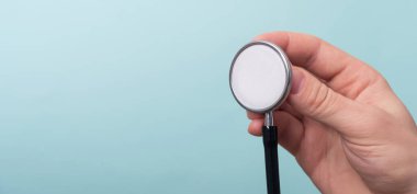 Açık mavi arka planda bir doktor elinde tıbbi steteskop. Tıp ve sağlık hizmetleri kavramı. Boşluğu kopyala, kapat, afiş
