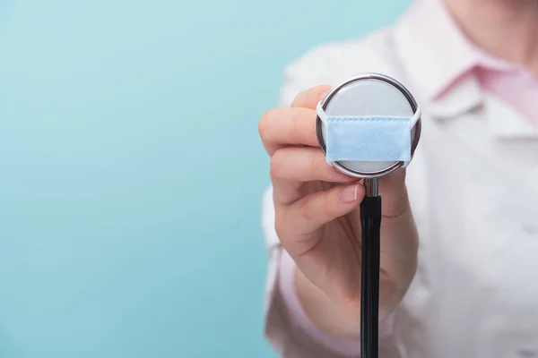 Médico Segurando Estetoscópio Médico Uma Máscara Proteção Facial Fundo Azul — Fotografia de Stock