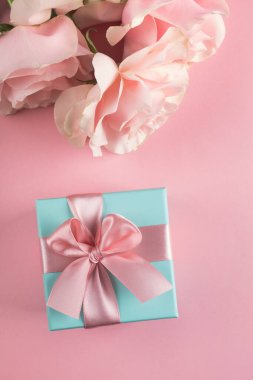 Pastel pembe arka planda gül çiçekleri olan hediye kutusu. Anneler günü, kadınlar günü, bahar konsepti. Üst görünüm, düz görünüm, dikey