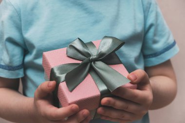 Küçük çocuk hediye kutusunu tutuyor. Anneler günü ya da doğum günü hediyesi. Kapat.