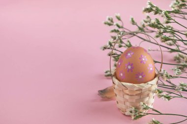 Paskalya yumurtası elle boyanmış ve bahar çiçekleri pembe pastel arka planda. Boşluğu kopyala, kapat, tebrik kartı