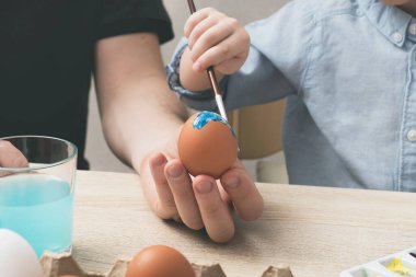 Paskalya yumurtalarını evde babasıyla boyayan çocuk. Paskalya için hazırlanıyorum, el yapımı dekor. Kapat.