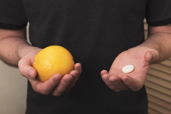 Man holding lemon fruit and pill vitamin C. Immunity system booster, nutritional supplement, healthy lifestyle. Close up