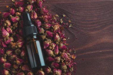 Aroma yağı ya da koyu ahşap arka planda gerekli gül serumu. Vücut ya da yüz bakımı, güzellik tedavisi, spa, organik kozmetik. Üst görünüm, kapat
