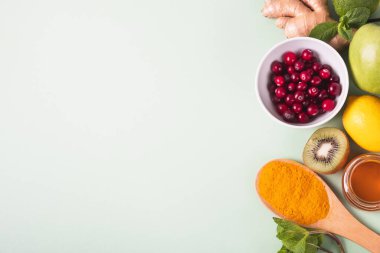 Yeşil arka planda bağışıklık geliştirmek için sağlıklı yiyecekler. Limon, bal, kızılcık, zencefil kökü, kivi, elma, nane, fındık ve zerdeçal. Sağlık, virüs önleme. Üst görünüm, düz görünüm, kopyalama alanı