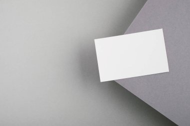 Gri arkaplandaki mesaj için boş kartvizit. Marka konsepti, tasarım modeli, minimalist kompozisyon. Üst görünüm, düz görünüm, kopyalama alanı