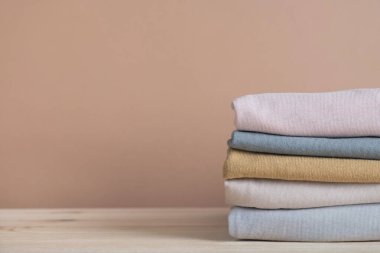 Pastel bej arka planda katlanmış giysiler. Moda, alışveriş ve satış konsepti. Boşluğu kopyala, kapat