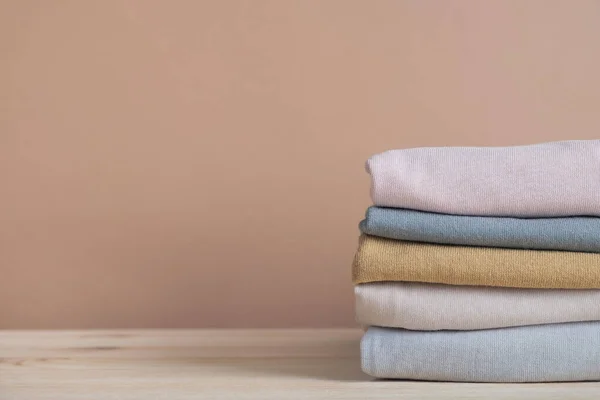 Pastel bej arka planda katlanmış giysiler. Moda, alışveriş ve satış konsepti. Boşluğu kopyala, kapat