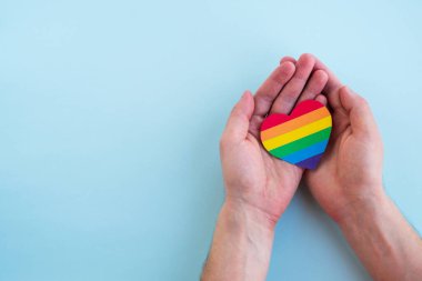 LGBT gökkuşağı kalbi insan ellerinde. Gurur ayı, sevgi ve hoşgörü konsepti. Üst görünüm, alanı kopyala