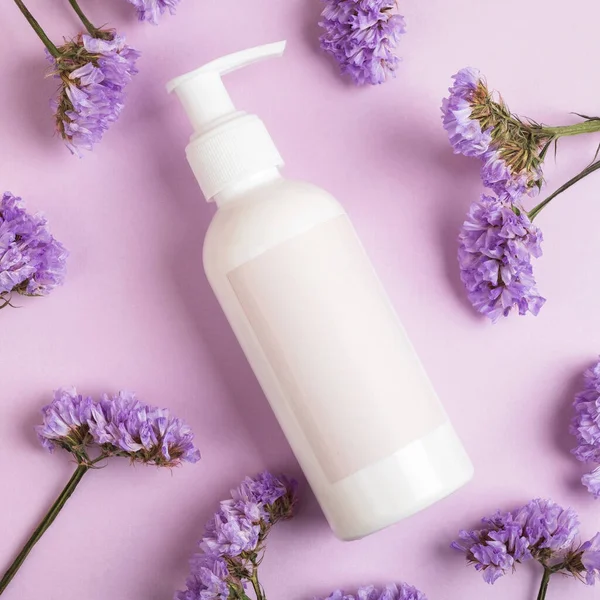 Cosmetische Fles Met Blanco Eetbaar Bloemen Pastelpaarse Achtergrond Schoonheidsbehandeling Concept — Stockfoto