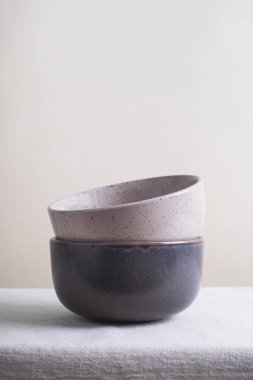 Masanın üzerinde keten masa örtüsü olan seramik kaseler. Yemek pişirme konsepti, ev dekorasyonu. En düşük bileşim, dikey