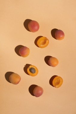 Ripe apricots with sunny shadows on pastel orange background. Summer food. Top view, flat lay, vertical