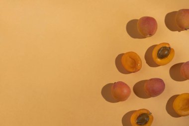 Ripe apricots with sunny shadows on pastel orange background. Summer fruits, organic seasonal vitamins food. Top view, flat lay, copy space
