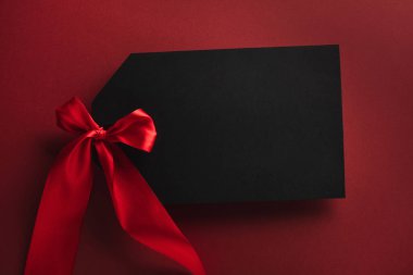 Kara Cuma indirimi. Kurdeleli boş etiket kartı, koyu kırmızı arka planda etiket modeli. Üst görünüm, düz görünüm, kopyalama alanı