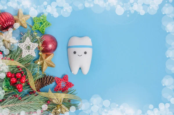 Dentistry banner background for Christmas and New Years with tooth model on blue background with Christmas decor with copy space.