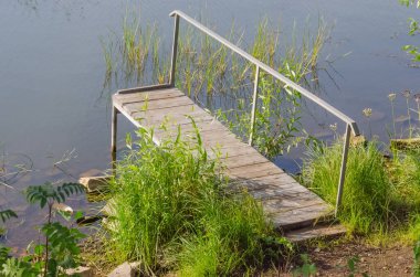 Yazın sessiz bir gölde yeşil çimenli küçük bir iskele.
