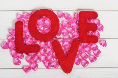 Sevgililer Günü geçmişi, beyaz ahşap bir arka planda pembe kalplerin sözcük aşkı.